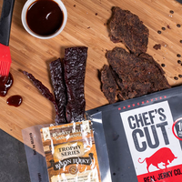 Two jerkies laying deliciously on a cutting board